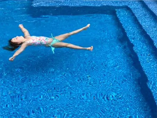 Girl floating in crystal-clear pool water after professional water testing
